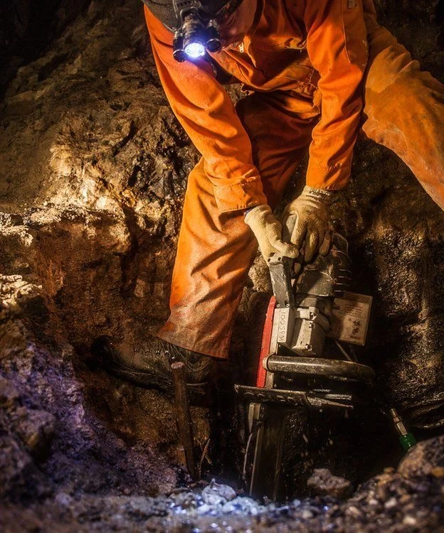 Rock drill in use underground during a drop raise operation
